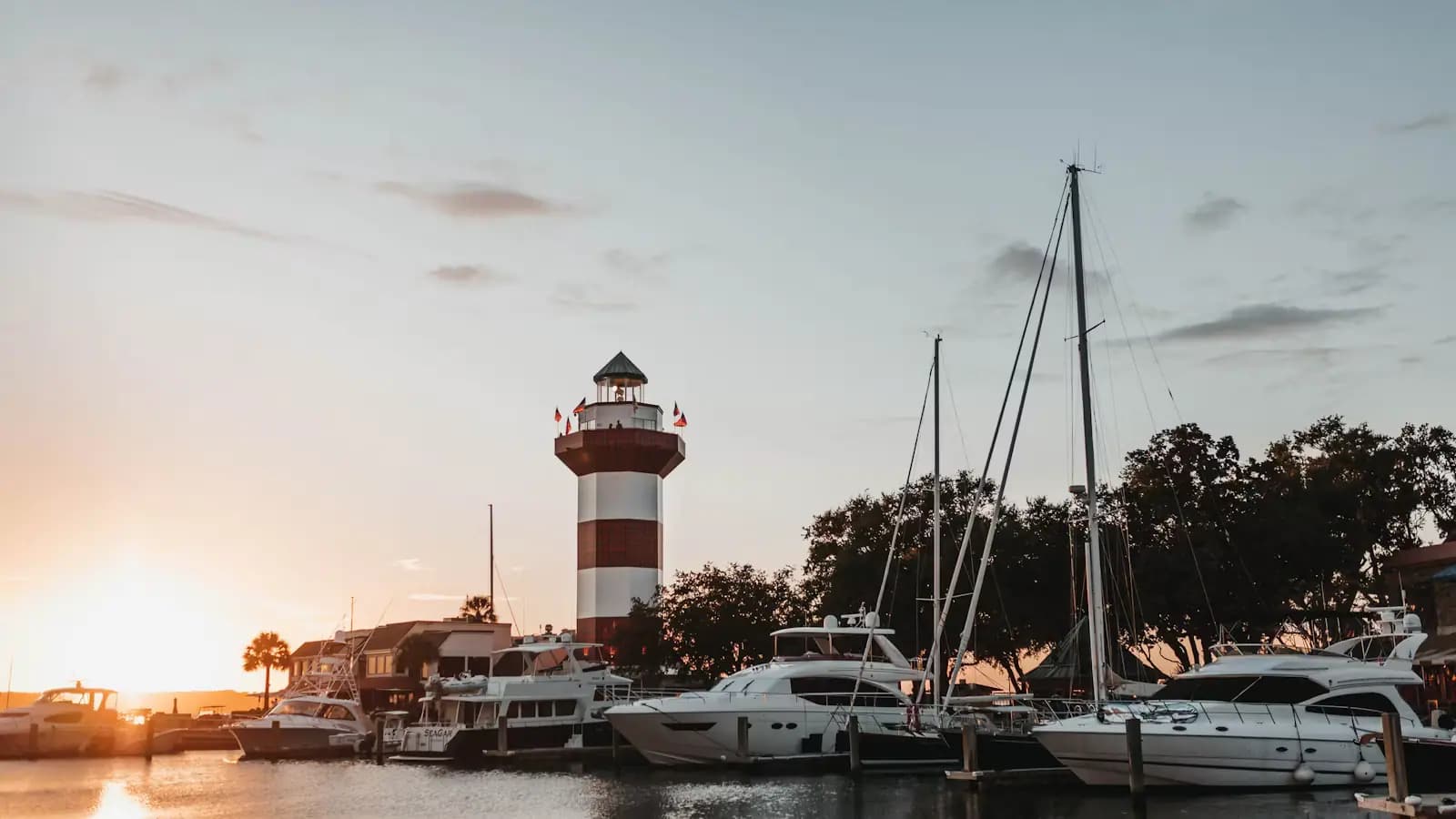 Boats moored in a harbour basin below a lighthouse tower