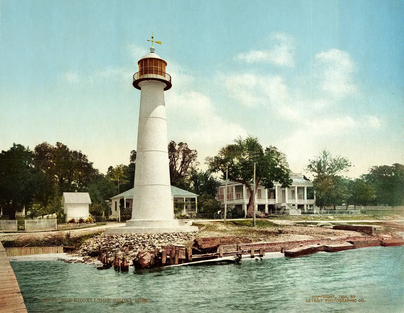 A lighthouse rising above a low building at the water's edge