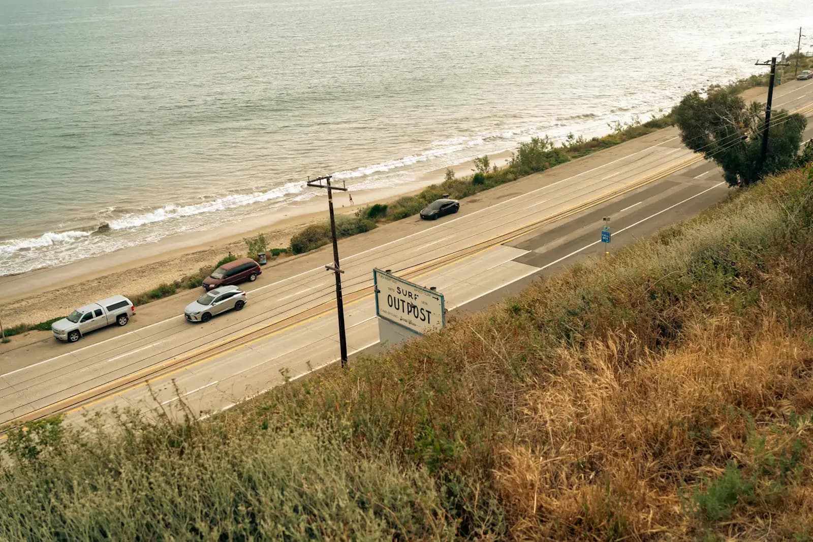 Cars moving along a coastal highway with open water alongside it