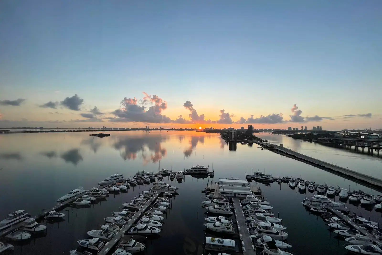 Rows of boats moored in a marina basin on flat water at first light