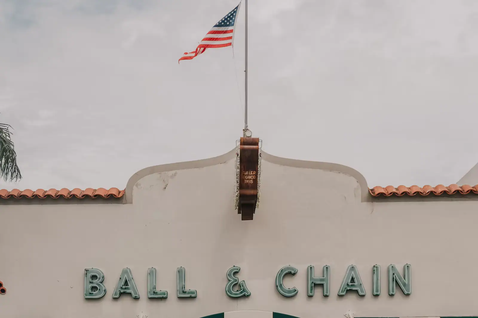 A striped awning and painted lettering above a storefront with a US flag on the wall