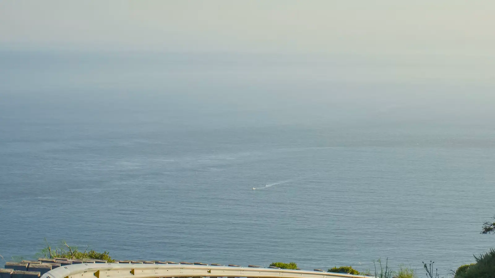 A curving coastal road running beside open water on a clear day